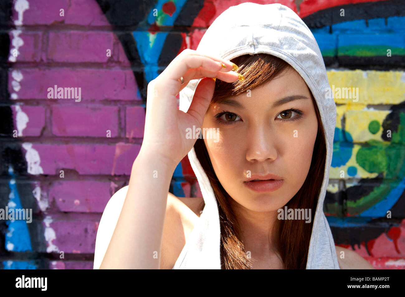 Teenage Girl With Hood Up In Front Of A Wall Of Graffiti Stock Photo