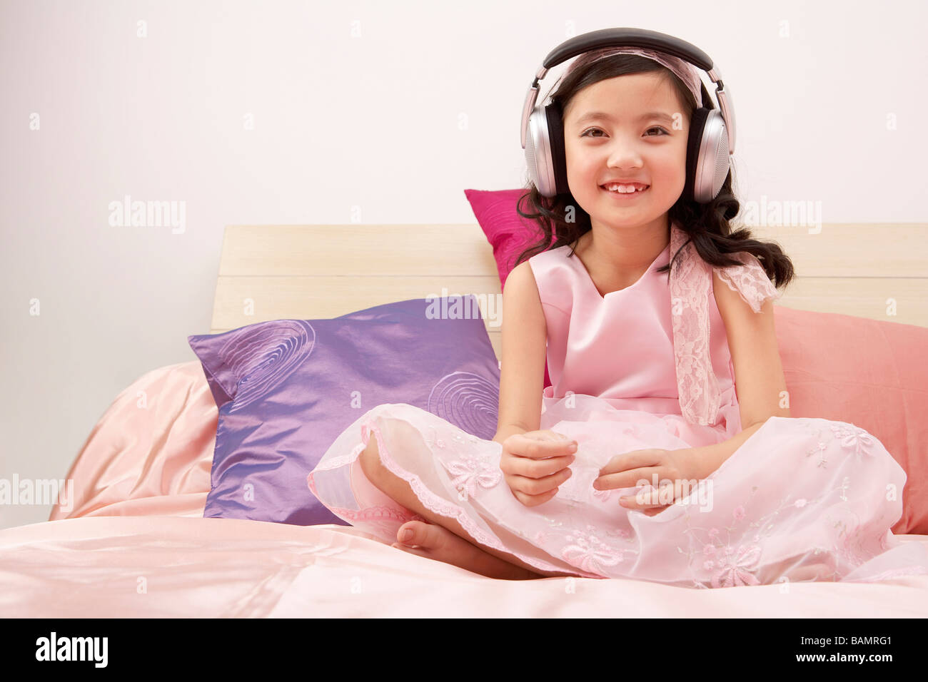 Girl Sitting On Bed Wearing Headphones Stock Photo - Alamy
