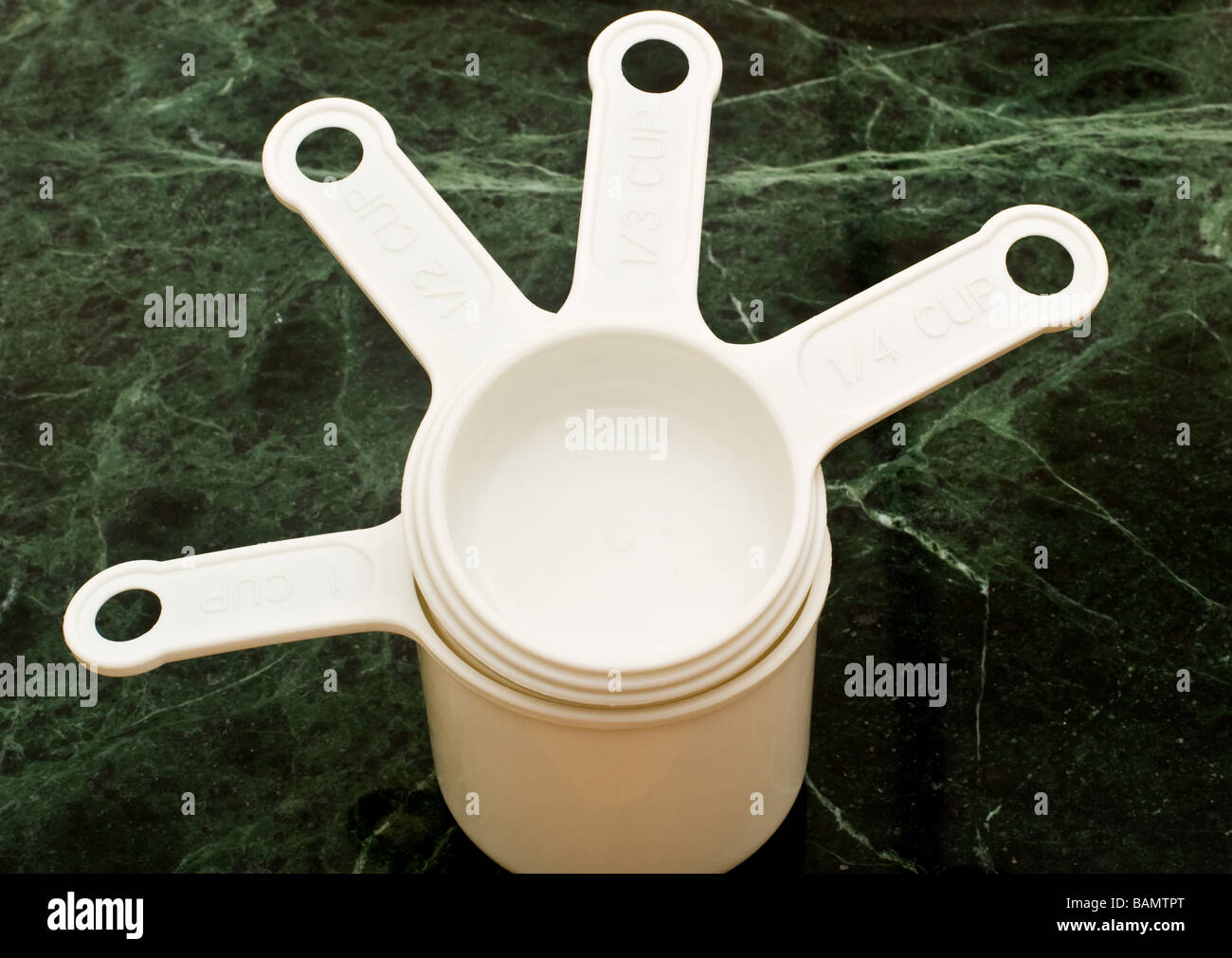 4 white plastic measuring cups of different sizes stacked from smallest