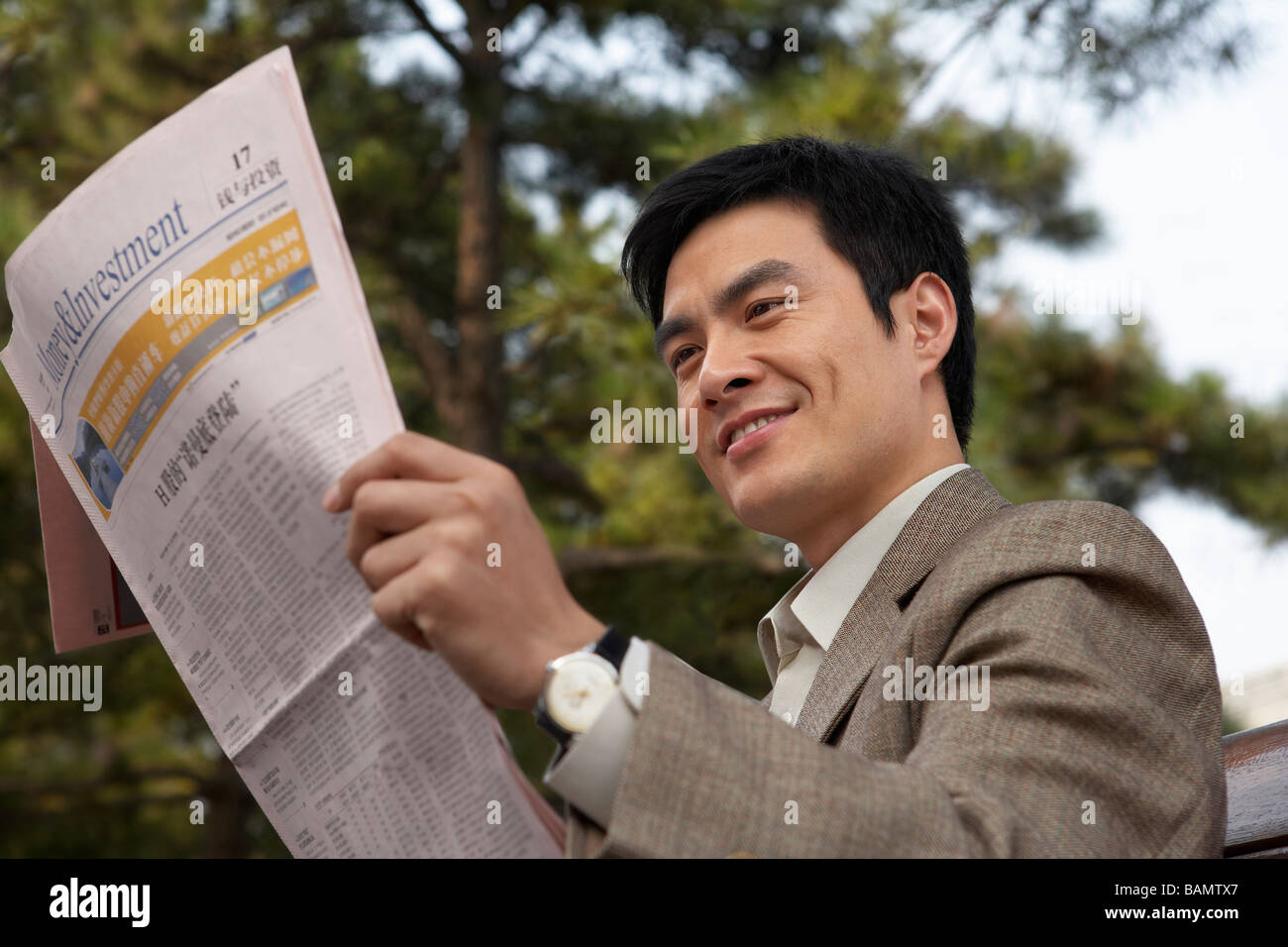 Businessman Sitting On A Park Bench Reading The Newspaper Stock Photo ...