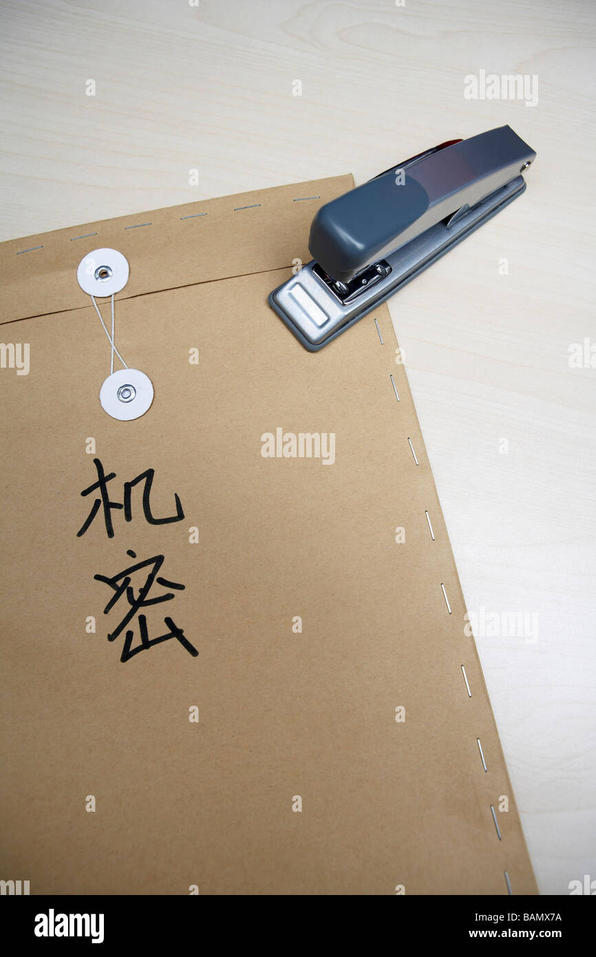 A stapler resting on a brown envelope that has 'top secret' in Chinese