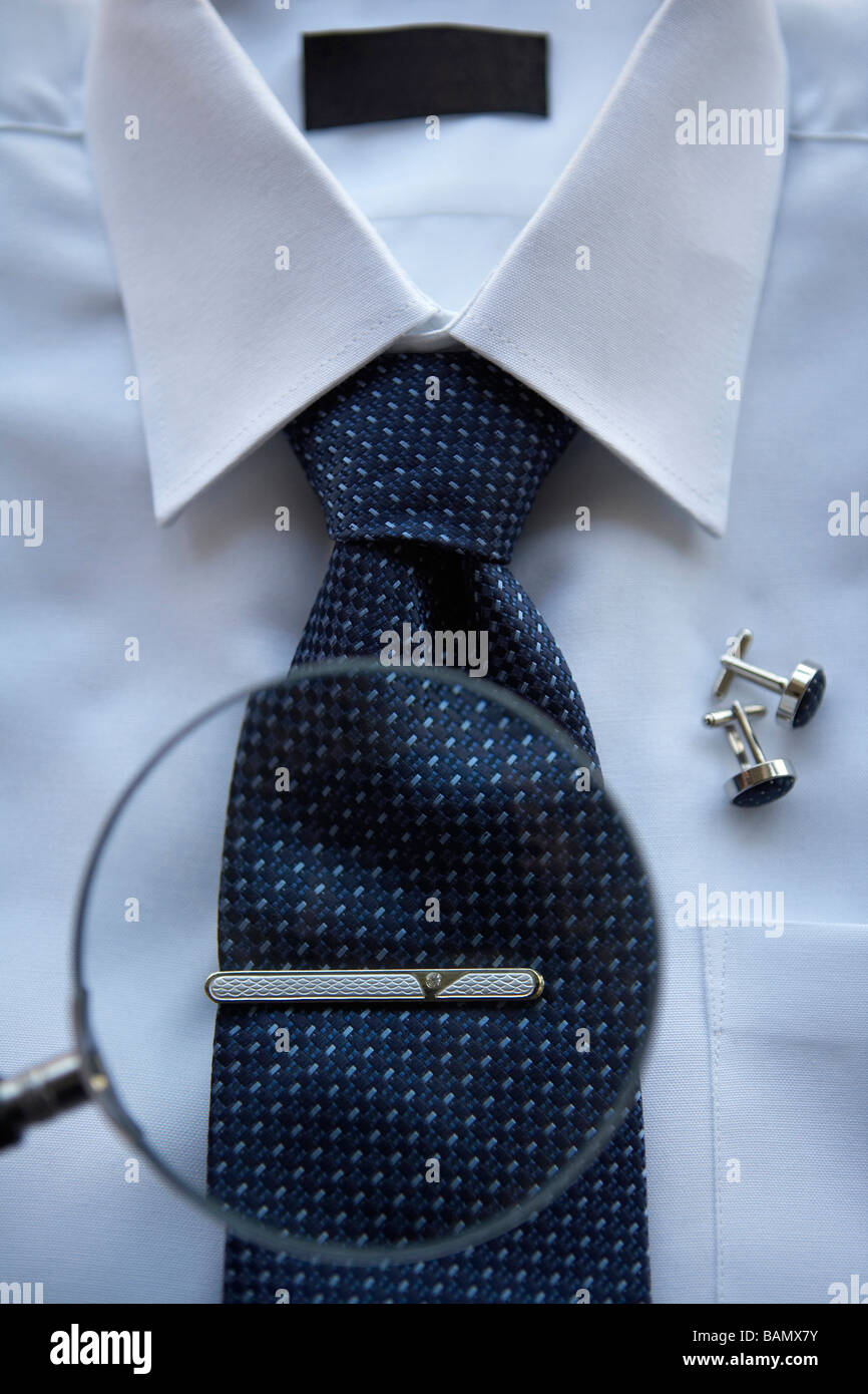 A Magnifying glass focused on a tie clip on a neck tie Stock Photo