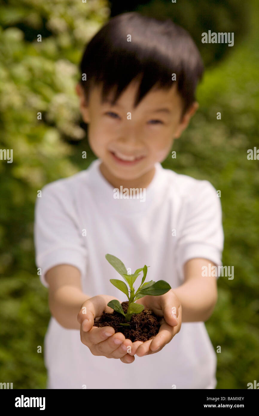 Young Boy Holding Plant In Both Hands Stock Photo - Alamy