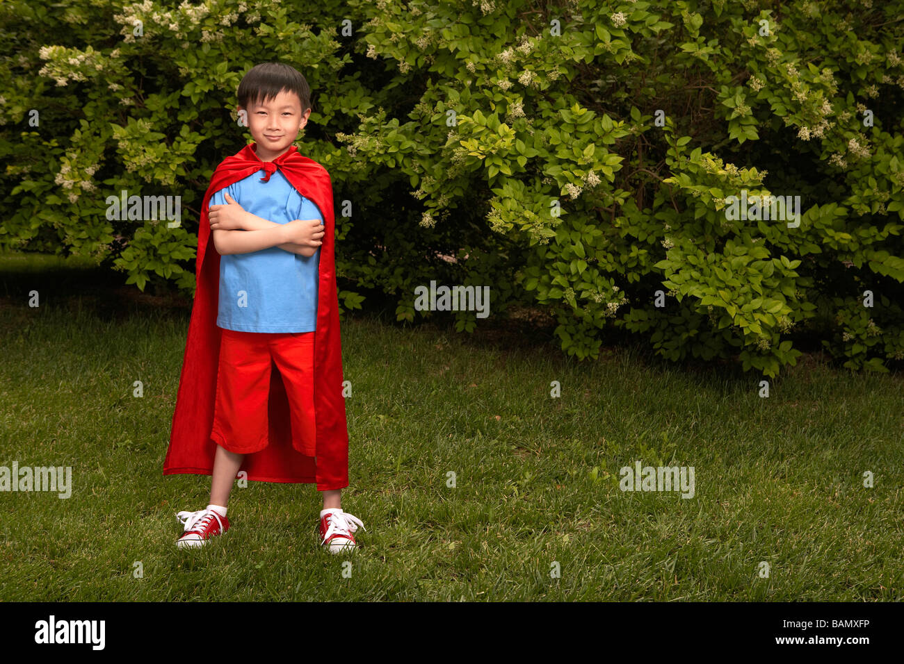 Boy In Red Cape Playing In Garden Stock Photo