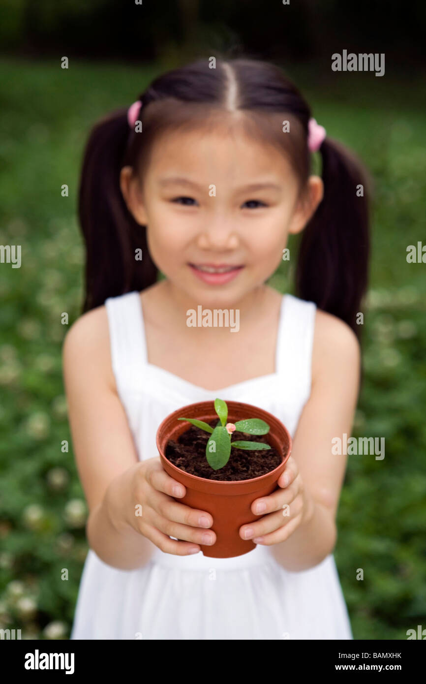 Young Girl Holding A Potted Plant In The Park Stock Photo - Alamy