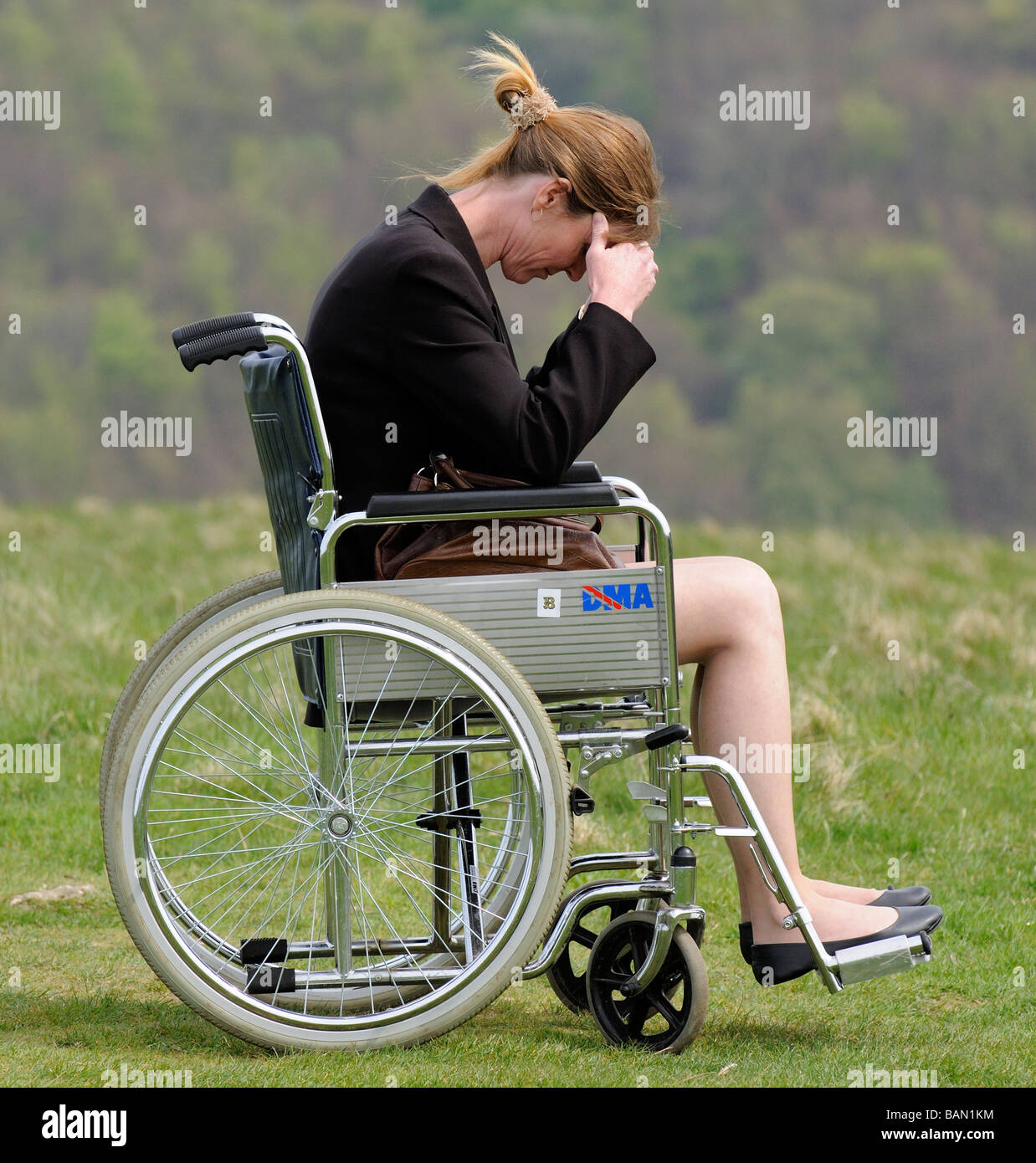 woman with head in hands sitting in a self propel dma wheelchair overlooking english countryside Stock Photo