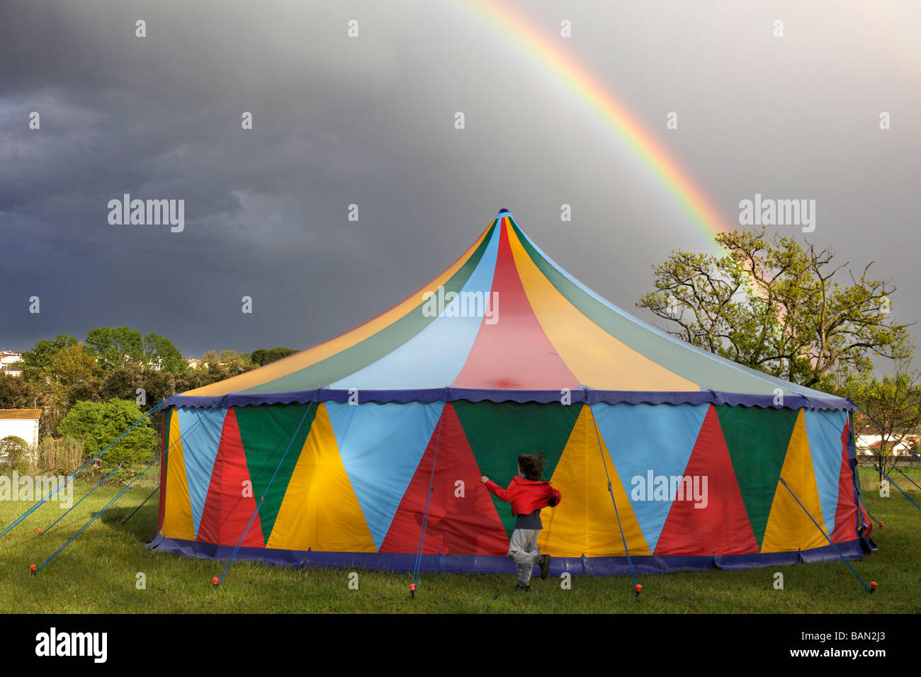 Colored circus tent in a rainy day with a rainbow on the sky Stock Photo