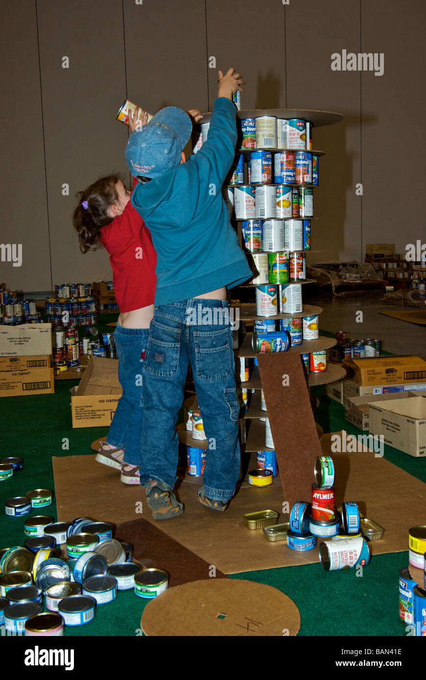 Canstruction hunger awareness charity event children trying their hand at making a sculpture from tins of donated canned food Stock Photo