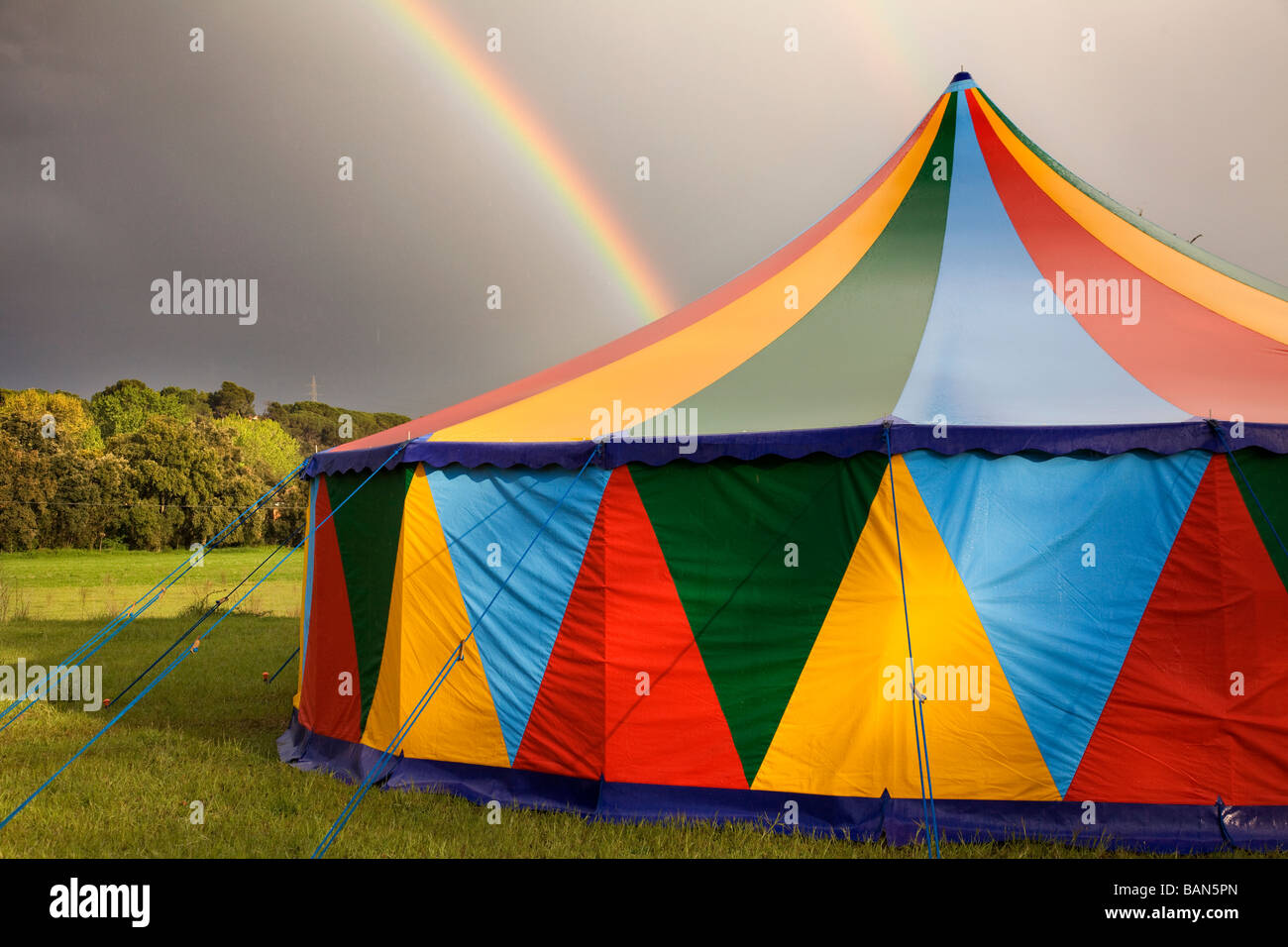 Colored circus tent in a rainy day with a rainbow on the sky Stock Photo