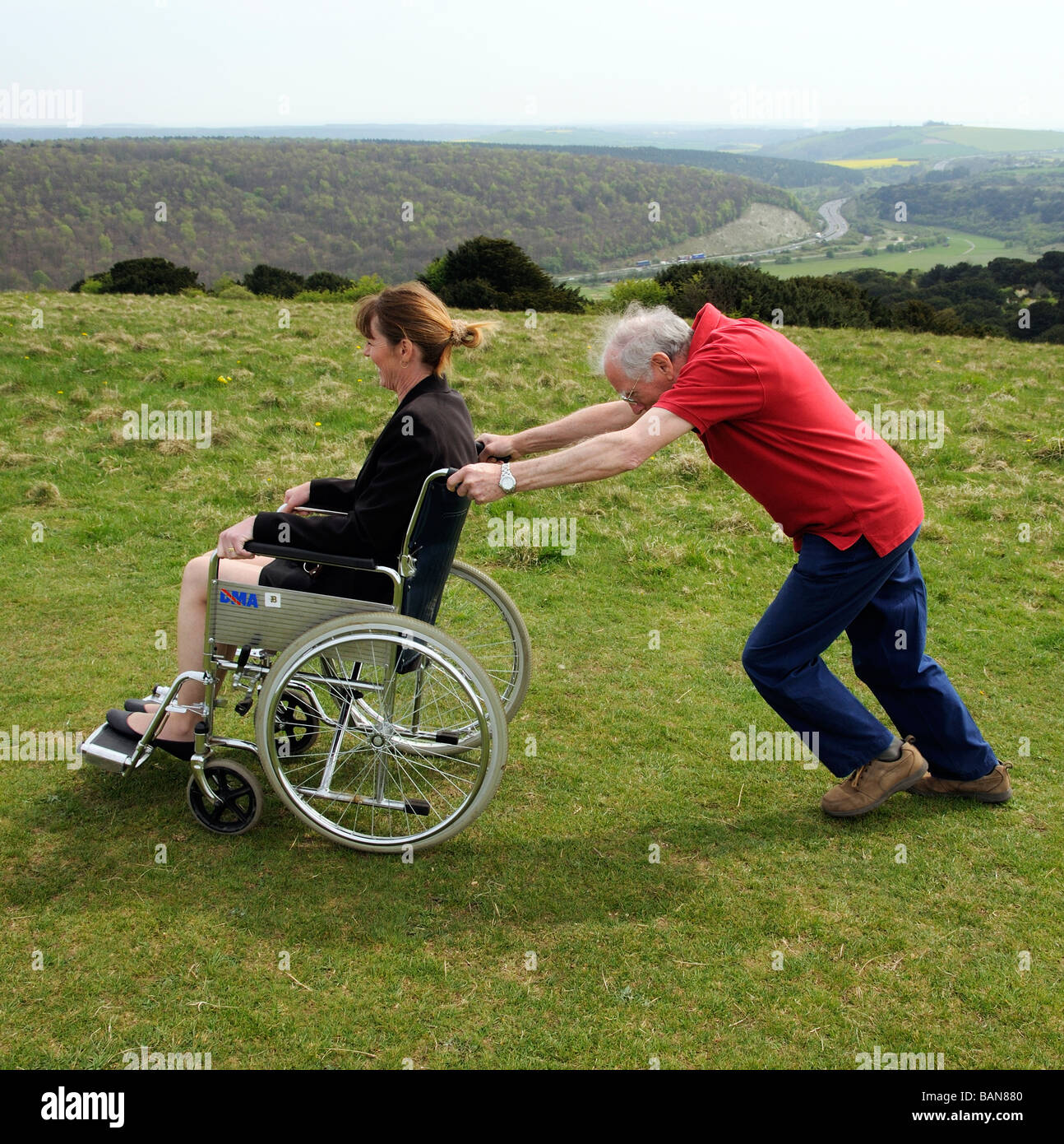 Carer pushing woman in a wheelchair in the English countryside UK Stock