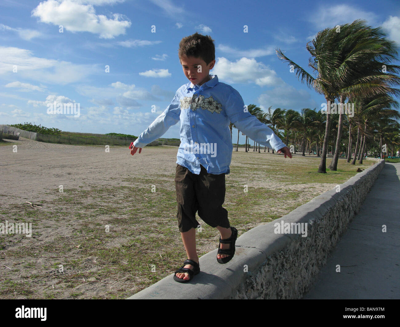 A young boy walking on a wall at the beach. Stock Photo