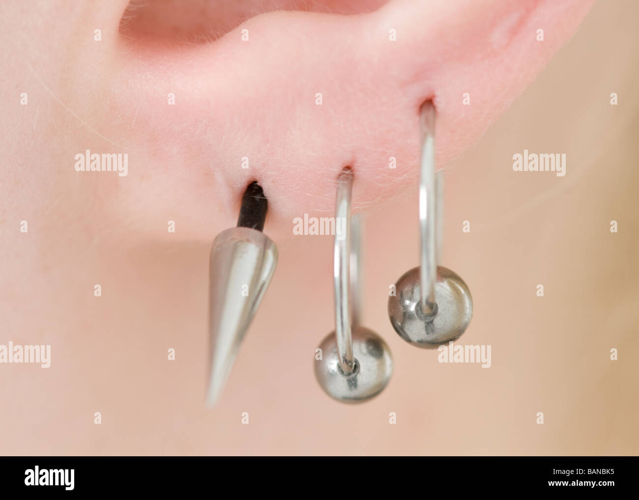 Ear piercings in a young blonde woman's ear in close up Stock Photo