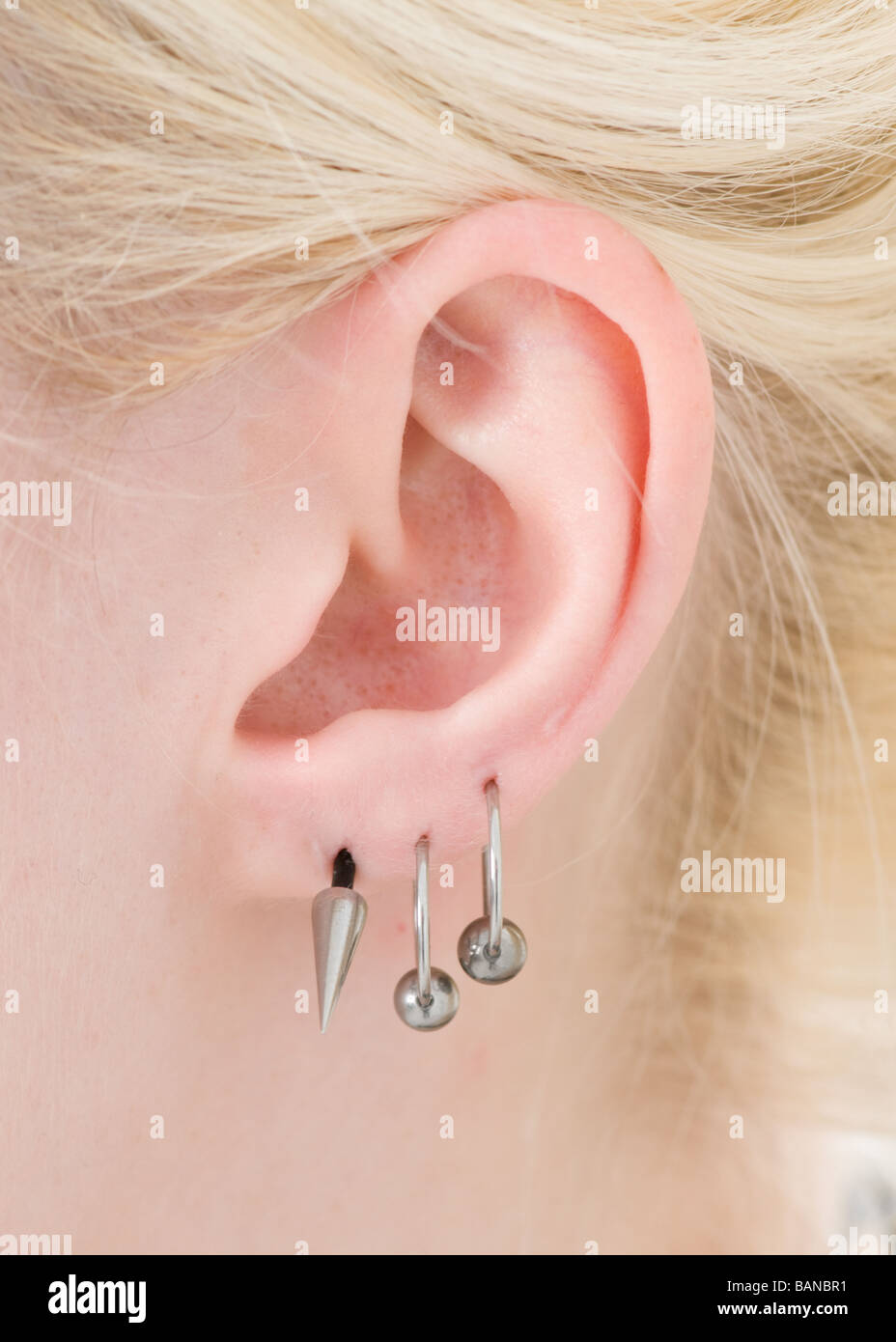 Ear piercings in a young blonde woman's ear Stock Photo