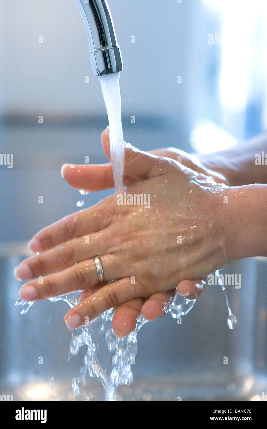 Woman is washing her hands under a tap Stock Photo