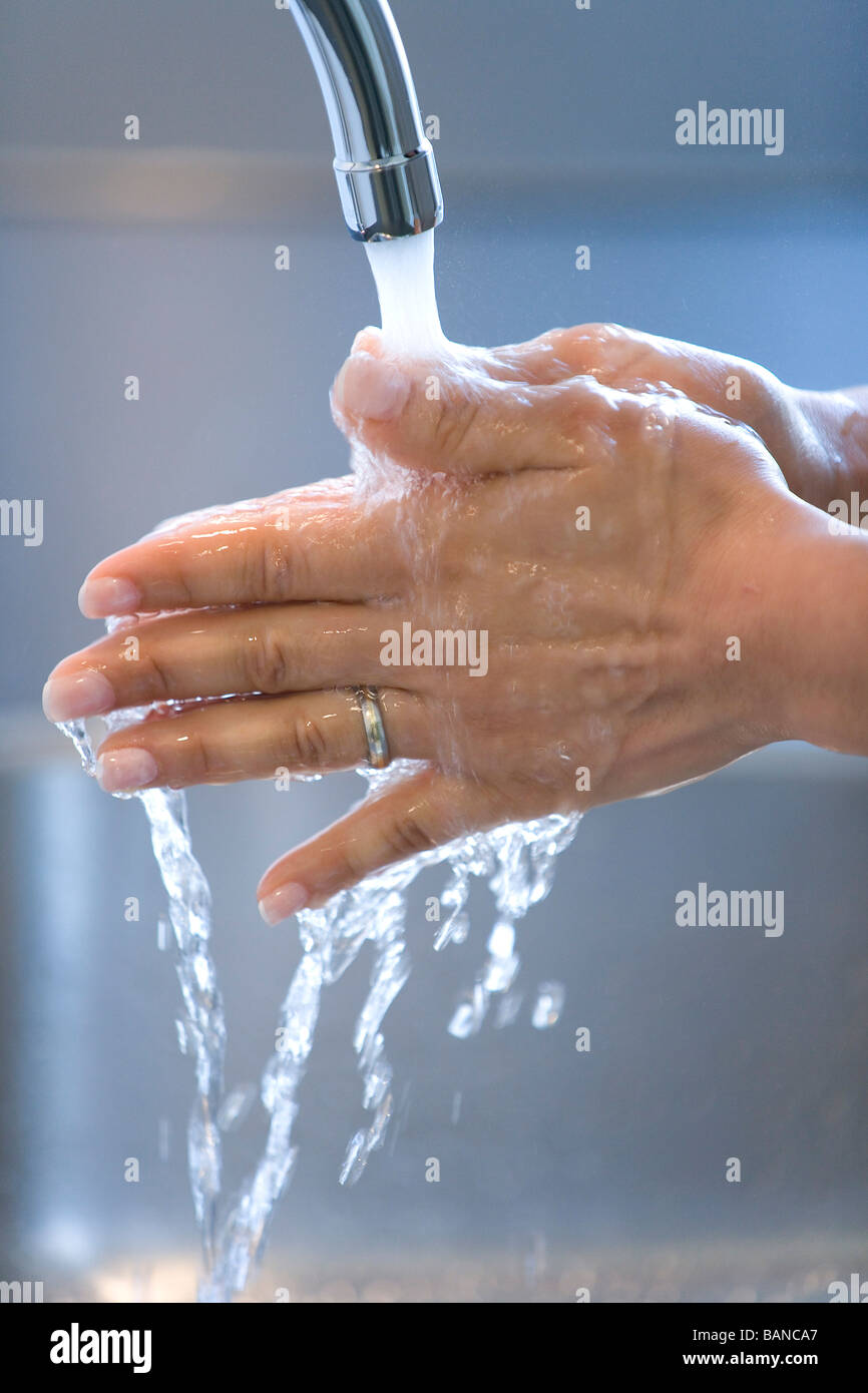 Woman is washing her hands under a tap Stock Photo