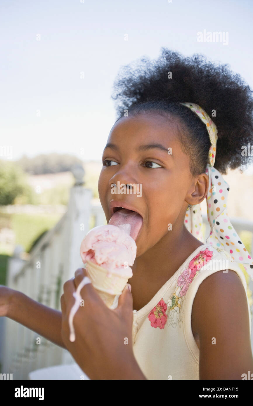 Mixed race girl licking melting ice cream cone Stock Photo Alamy