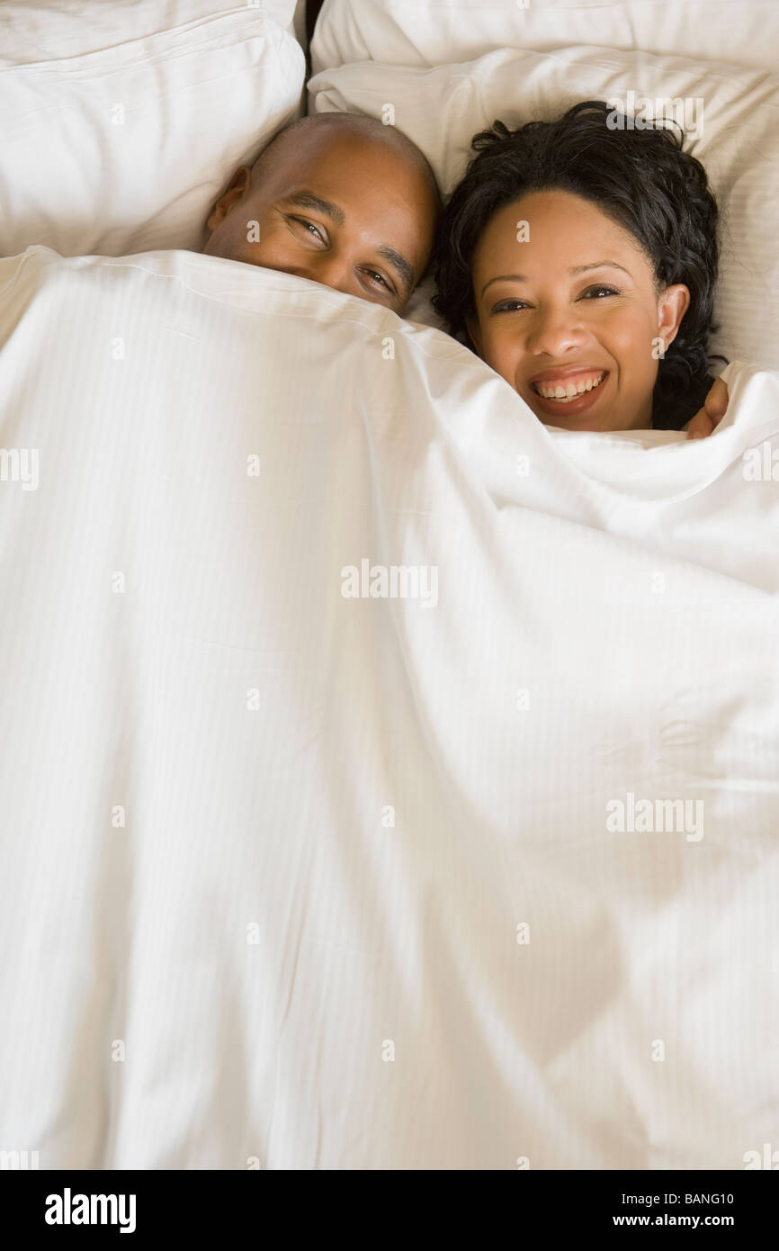 African couple in bed under blanket Stock Photo - Alamy