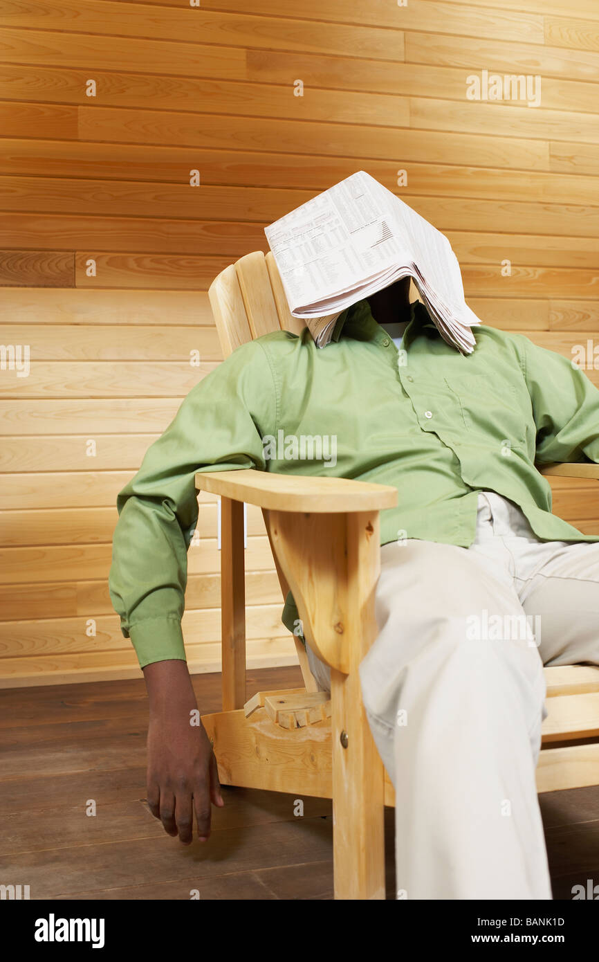 African man with newspaper over face Stock Photo