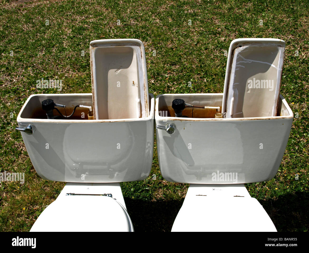 two toilets toilet with bowl and flush, lid is up and down, toilets sitting on a yard ready to