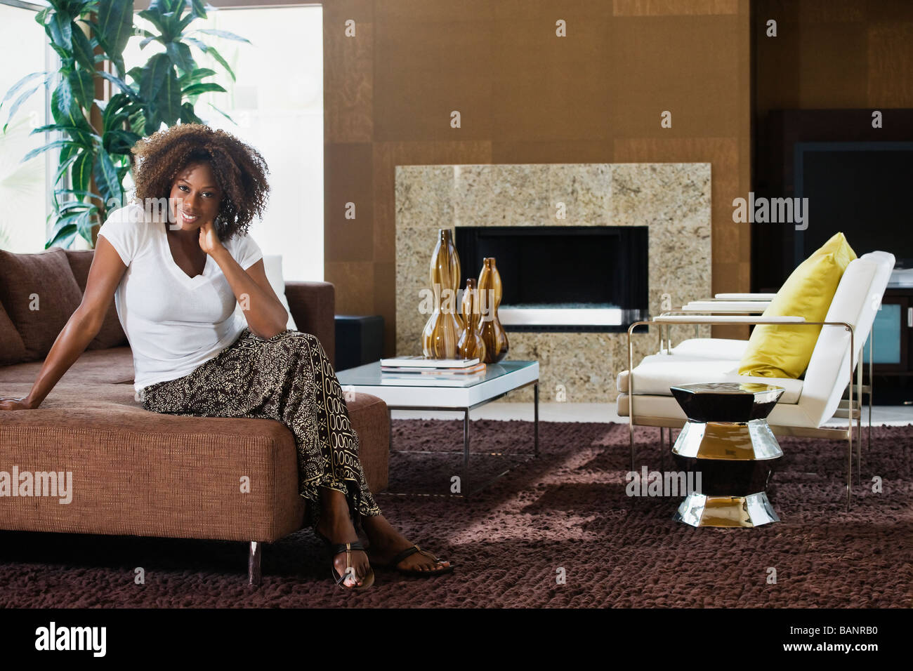 African woman sitting in modern living room Stock Photo - Alamy