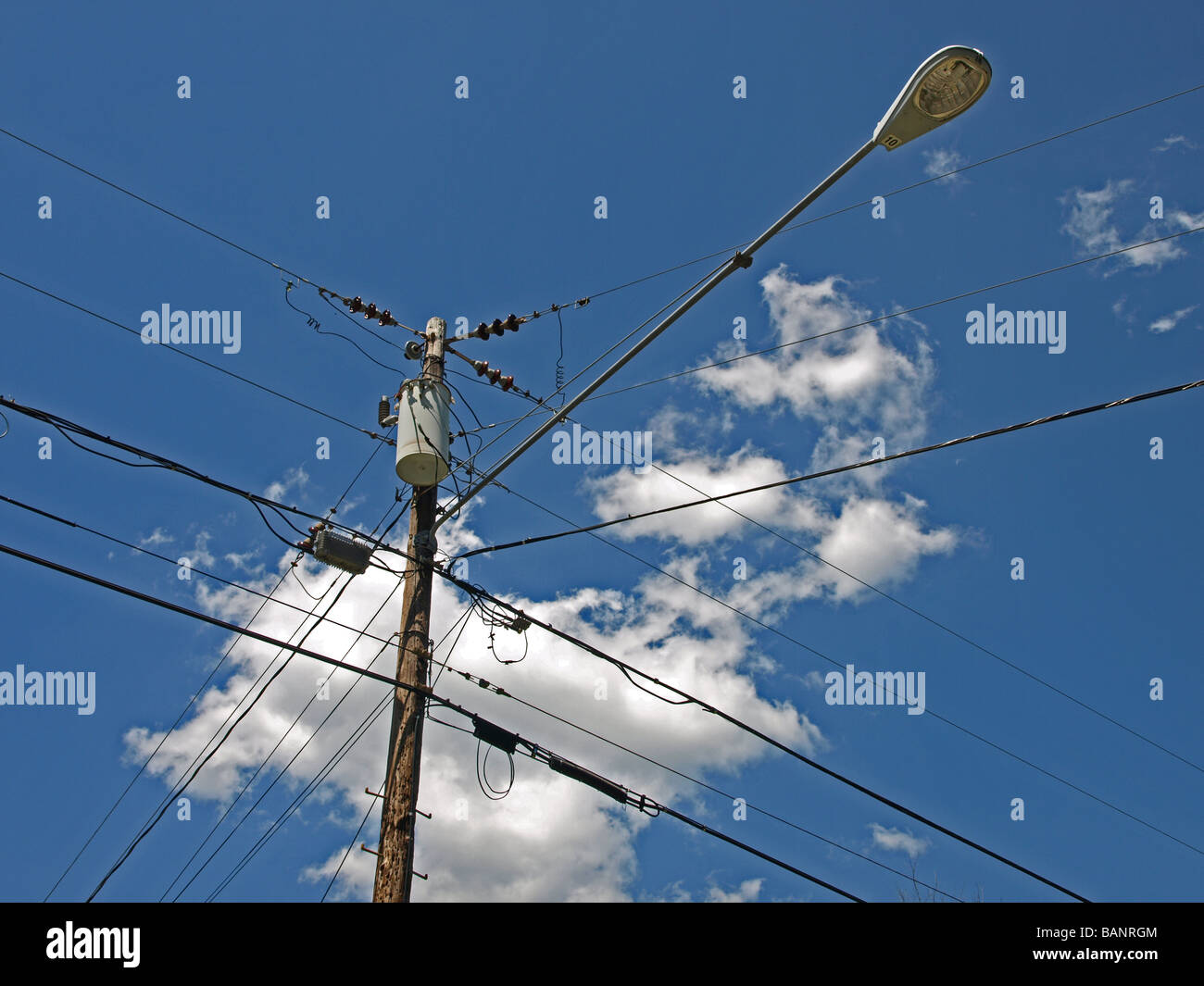 power utility and street light pole with wires, clouds, blue sky, generator, electrical, telephone and cable, looking up, lamp Stock Photo