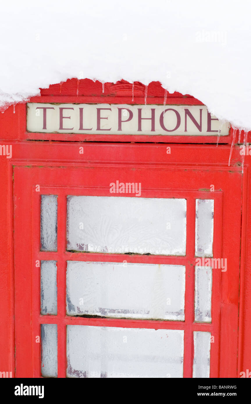 A red telephone box in deep snow by the roadside in the village of Crathie, outside Balmoral Castle, Scottish Highlands. Stock Photo