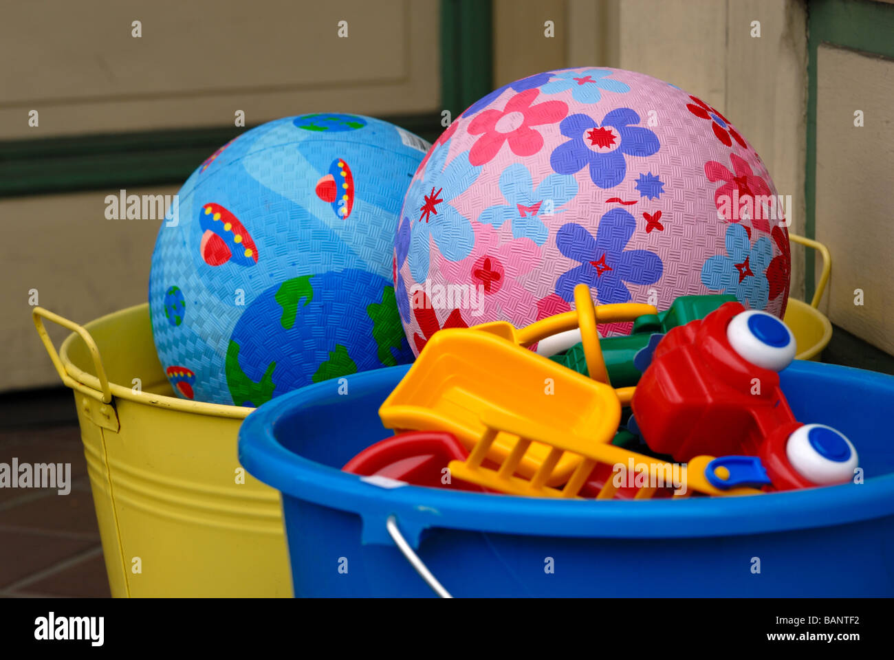Colorful balls and toys are piled in brightly colored buckets on the sidewalk outside of a toy store. Stock Photo