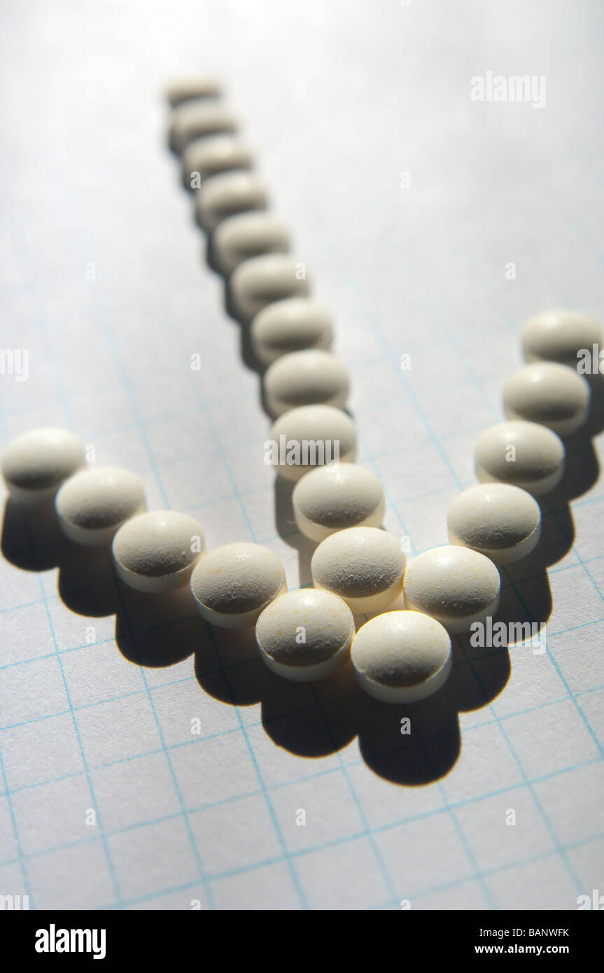 Pills on graph paper aligned to form an arrow pointer. Stock Photo