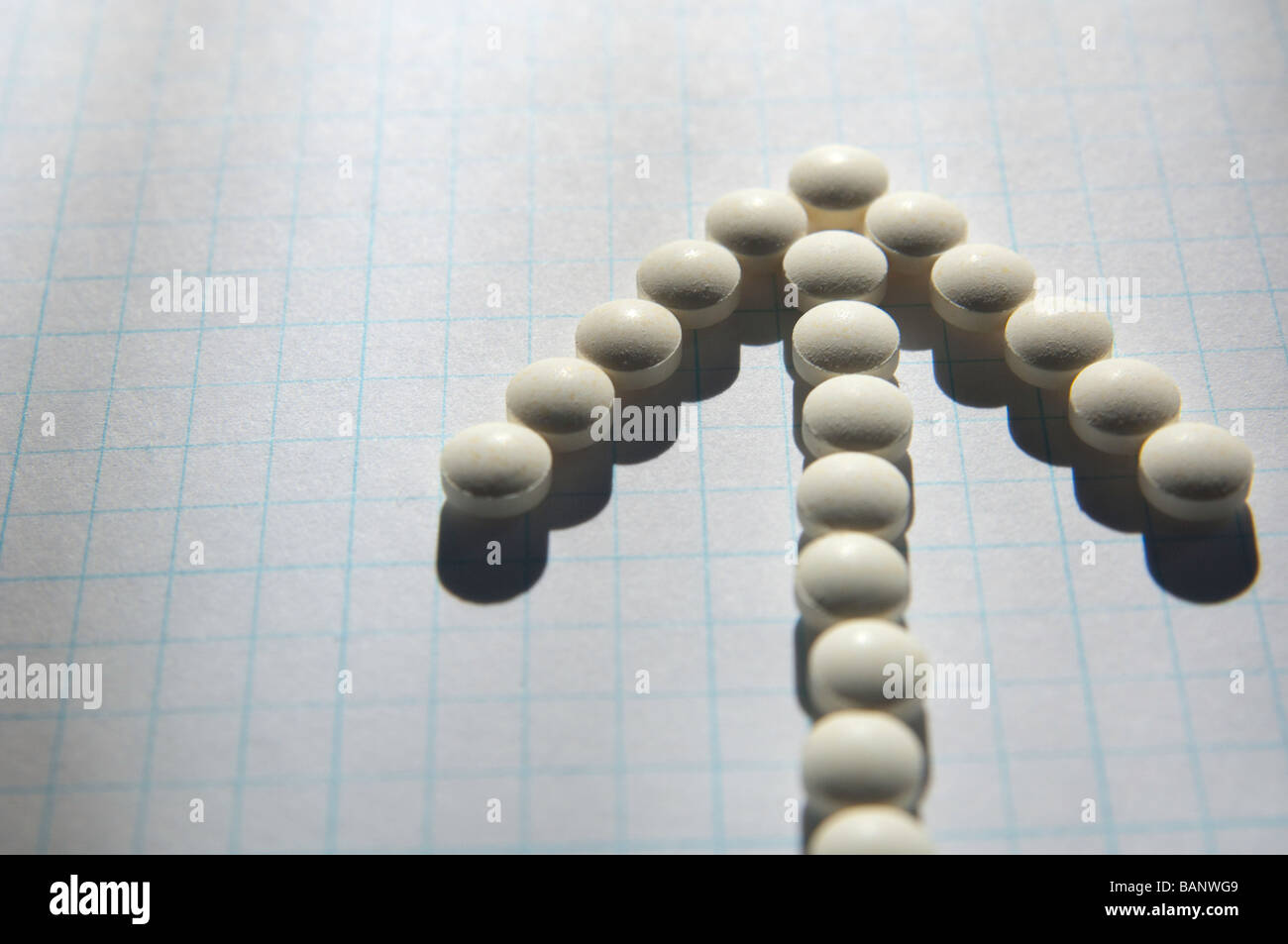 Folic acid pills on graph paper aligned to form an arrow pointer. Stock Photo