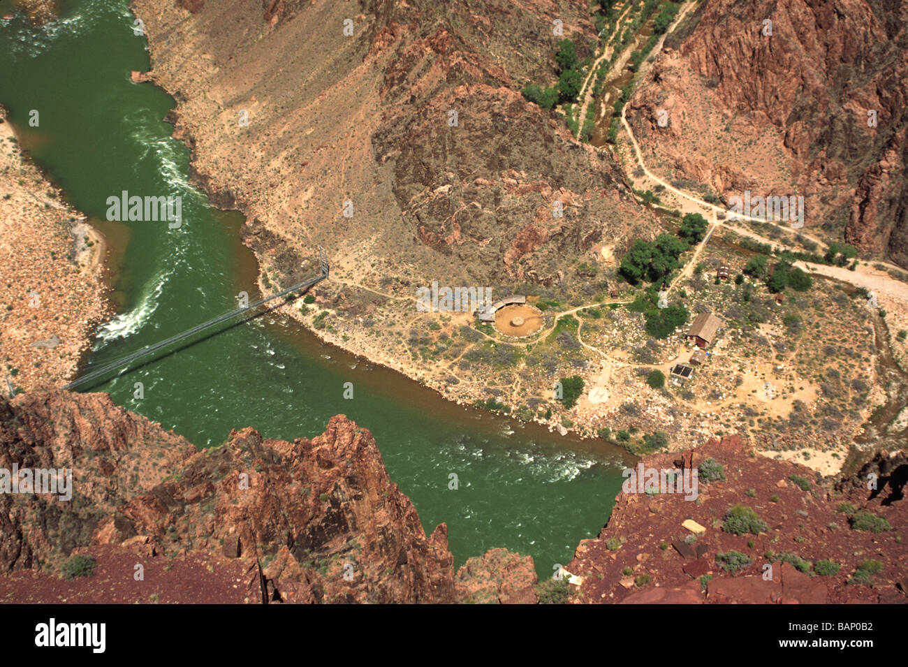 The green waters of the mighty COLORADO RIVER flow under a suspension bridge at PHANTOM RANCH ARIZONA Stock Photo