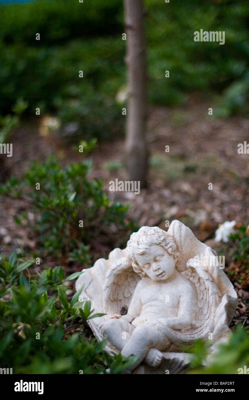 Small cherub statue set in a garden Stock Photo Alamy