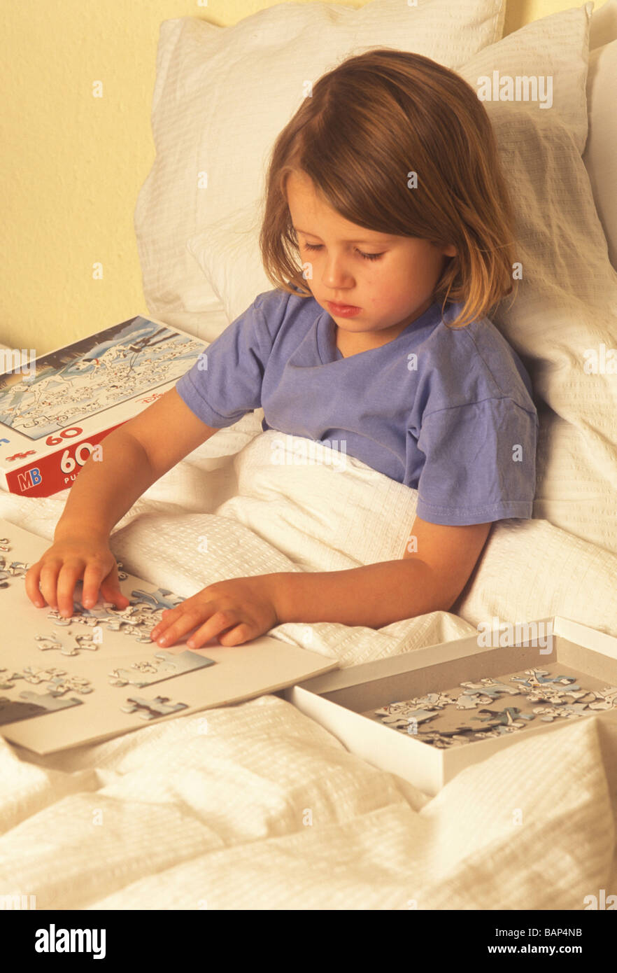 child doing a jigsaw puzzle sitting up in bed convalescing Stock Photo