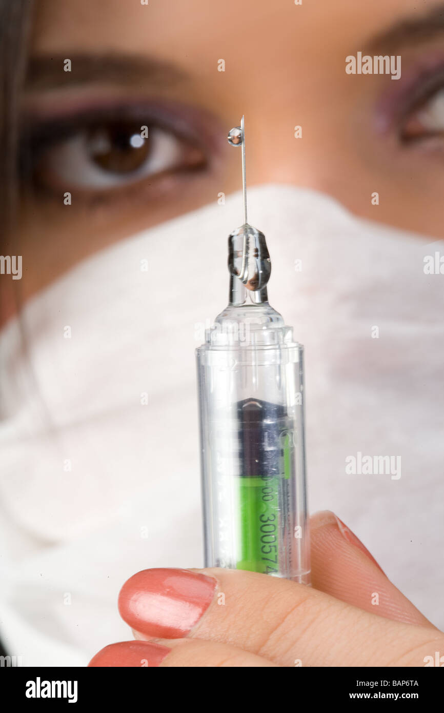 close up shot of syringe with a drop of liquid, nurse looking in the background Stock Photo