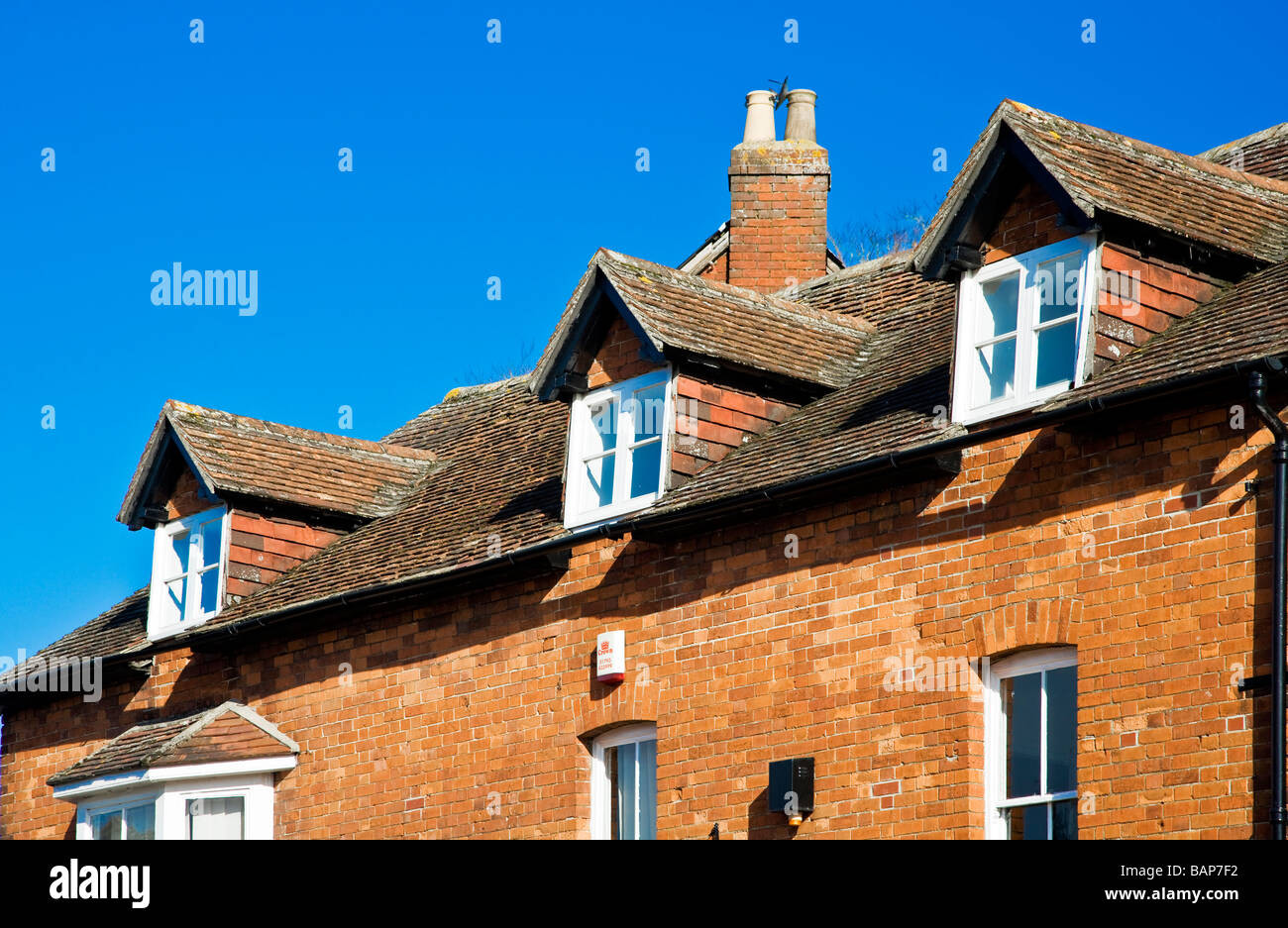 A row of three gable fronted dormer windows in a tiled roof in Wiltshire England UK Stock Photo