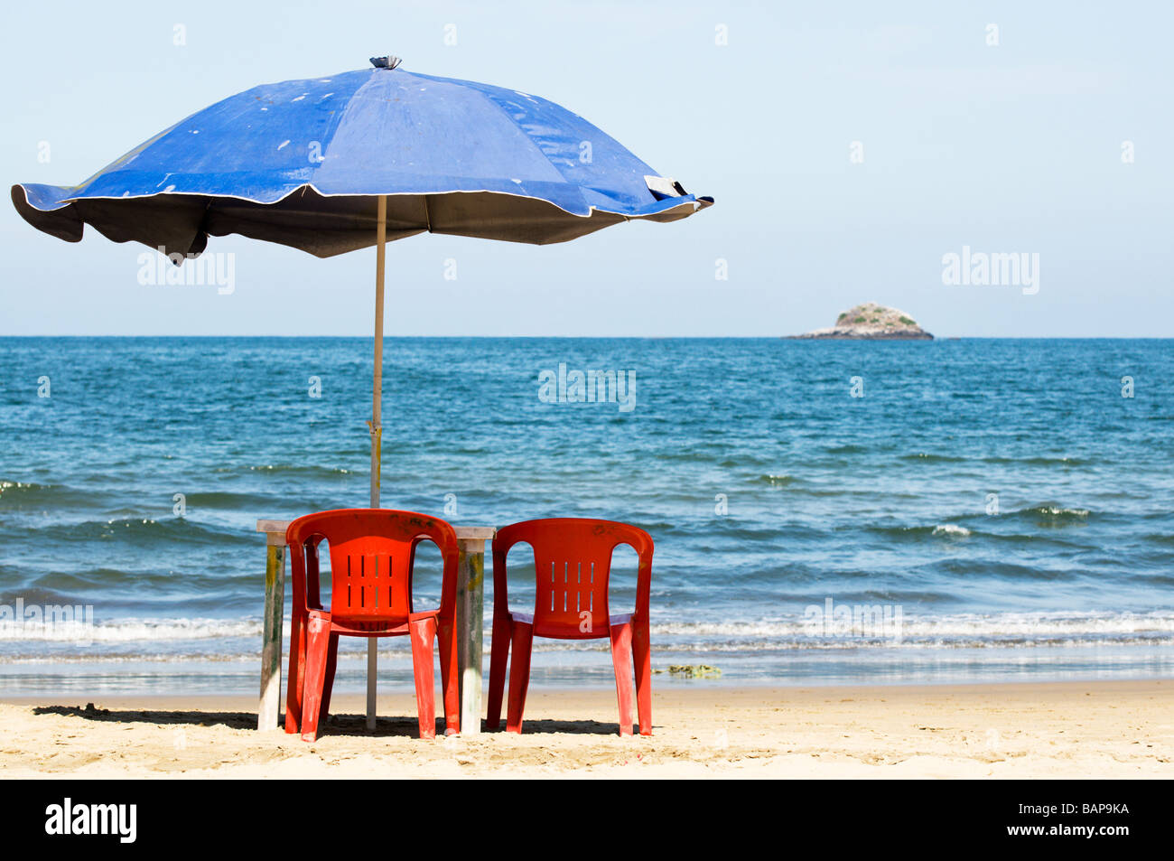 Two empty chairs and an umbrella sit unused on a sandy beach in Mexico. Stock Photo