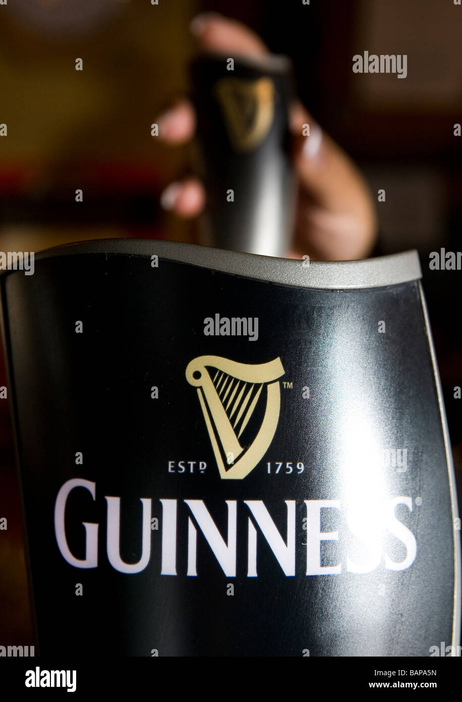 The Guinness Harp is seen on the pump as a pint is poured Stock Photo