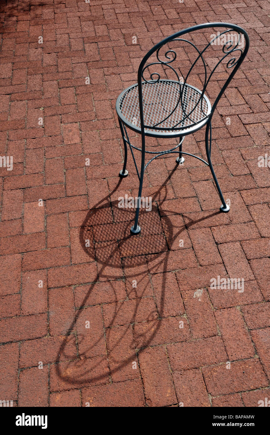 Interesting shadows formed by metal chairson red brick. Stock Photo