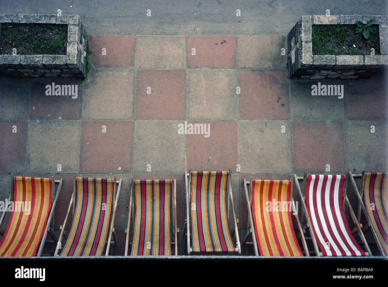Graphic composition from above of stripped beach chairs and a grid of patio tiles Stock Photo