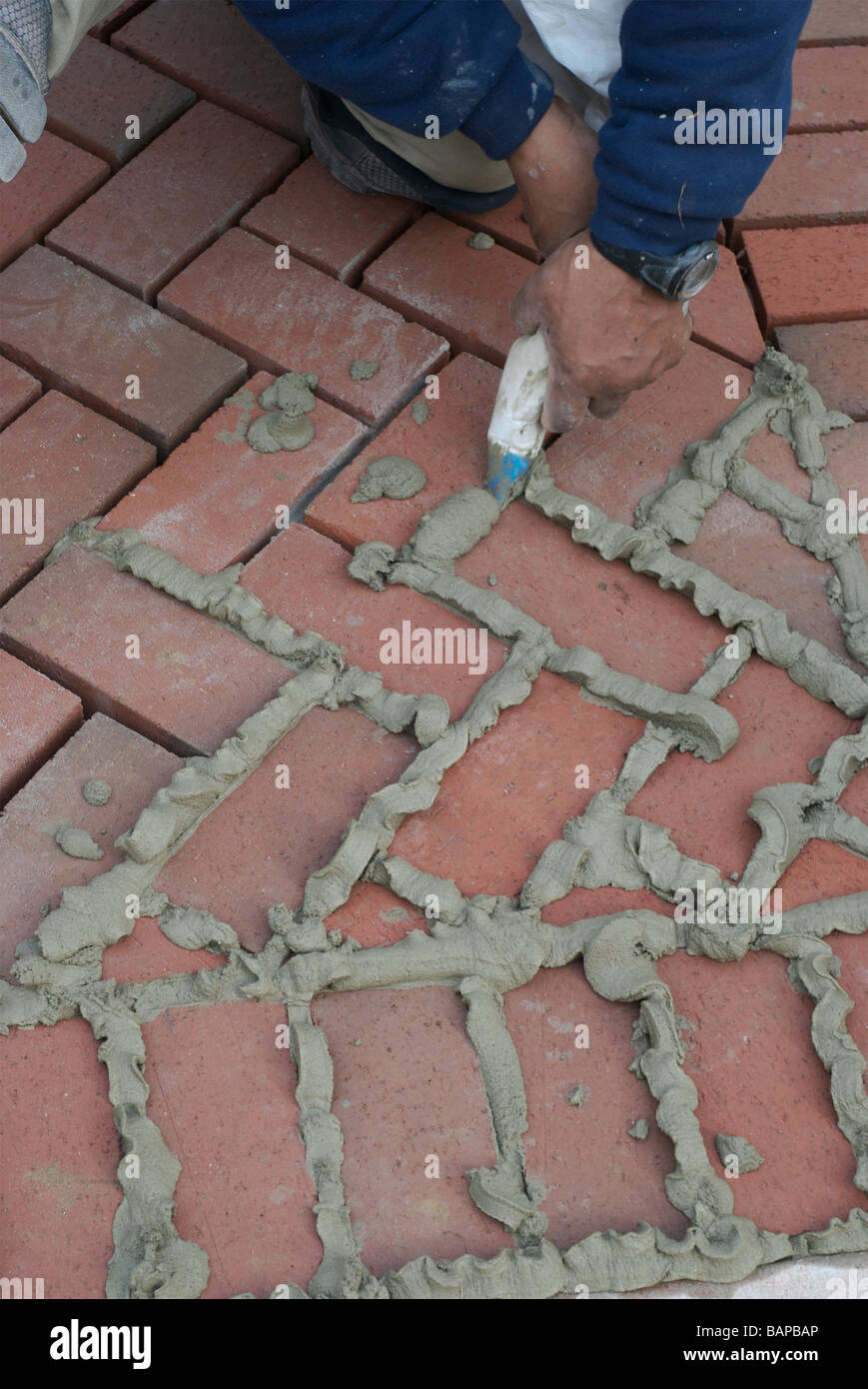 Using a squeeze bag to grout between paving bricks. Stock Photo