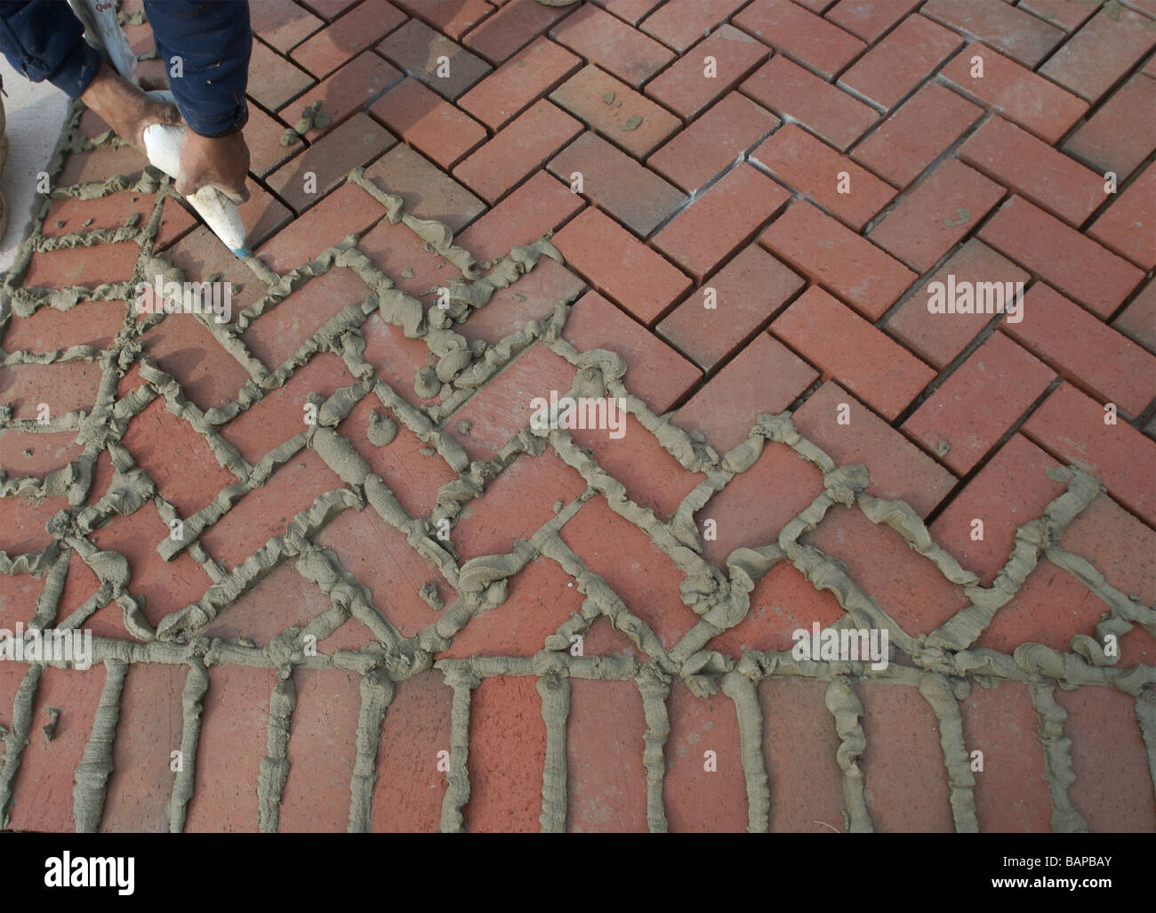 Using a squeeze bag to grout between paving bricks. Stock Photo
