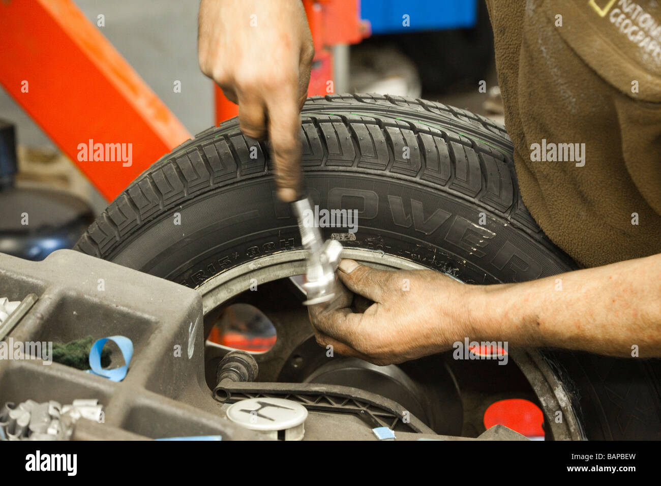 man fitting balancing weights to wheel Stock Photo Alamy