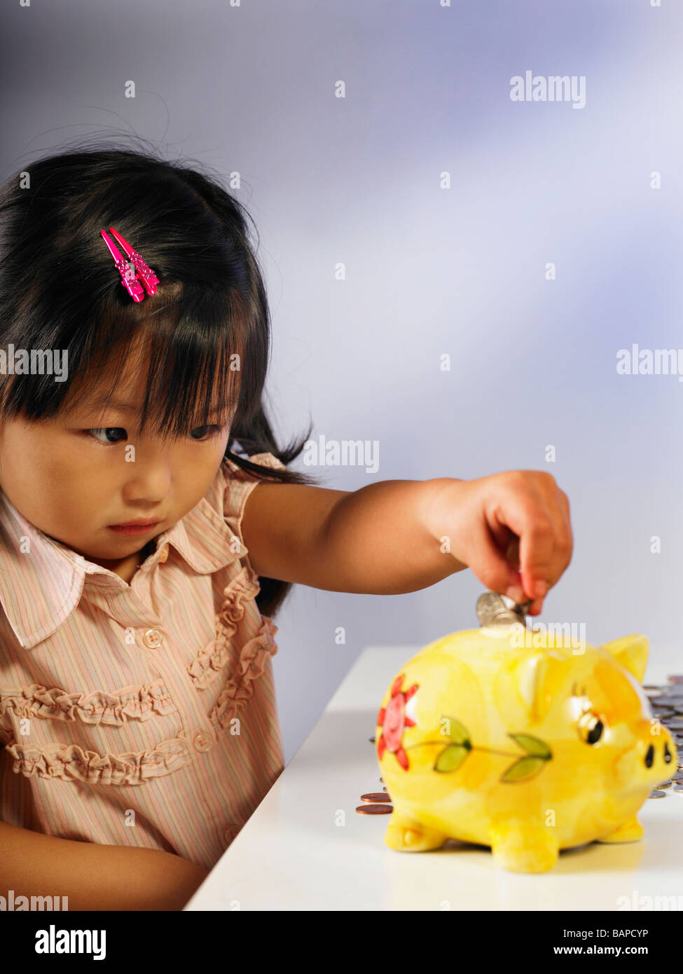 girl putting money into piggy bank Stock Photo - Alamy