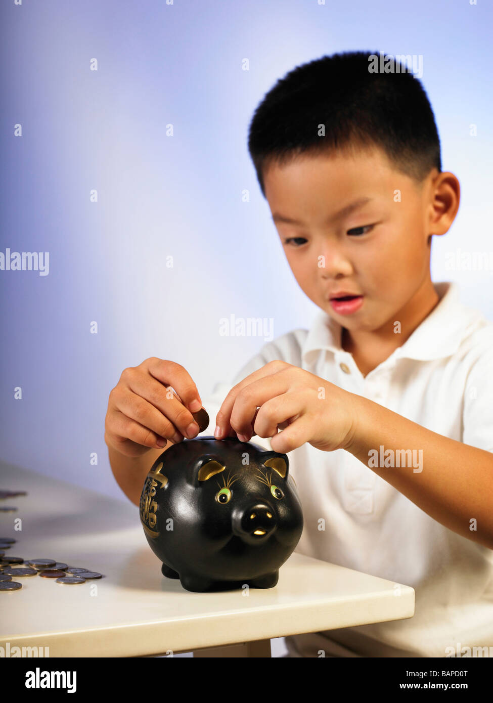boy putting coin to the black color piggy bank Stock Photo - Alamy