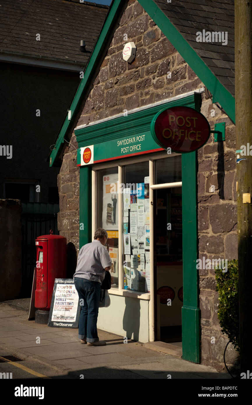 A woman outside the small rural village  post office in St David s city Pembrokeshire Wales UK Stock Photo