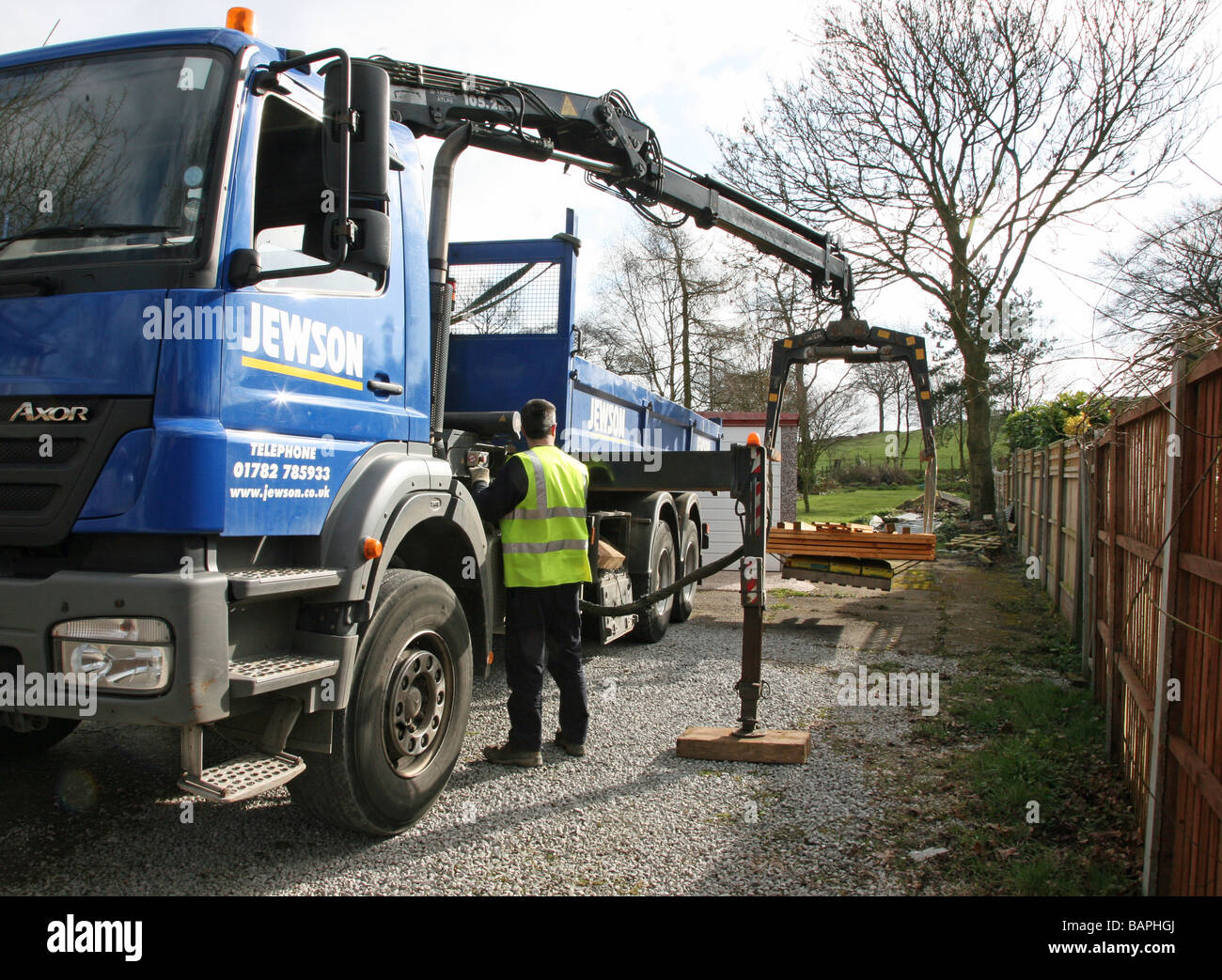 A builder's merchant delivering wooden fence panels with a lorry with a hydraulic lifting arm Stock Photo