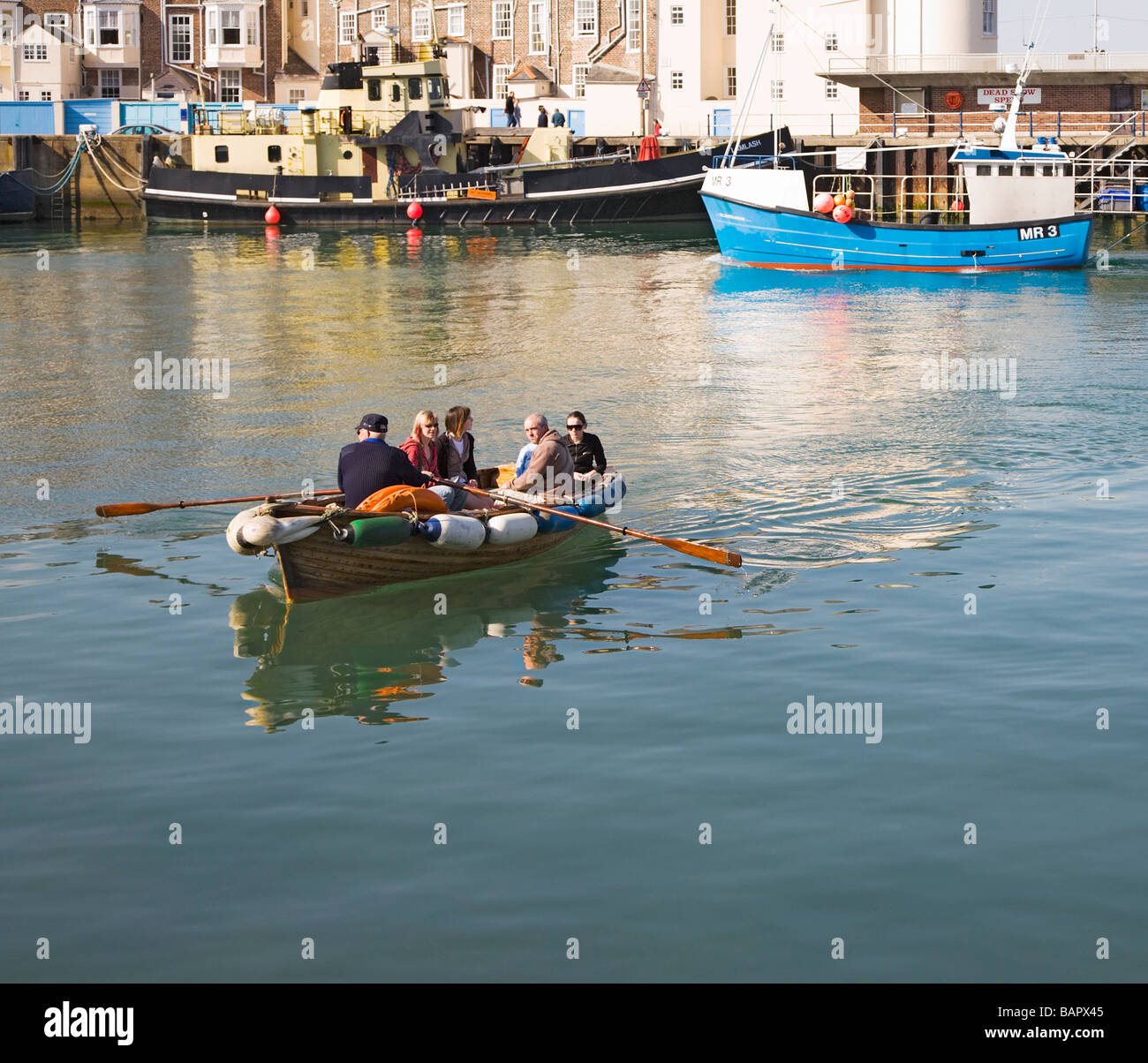 People in the rowing boat taxi ferry that goes from one side of Weymouth harbour to the other. Dorset. UK. Stock Photo