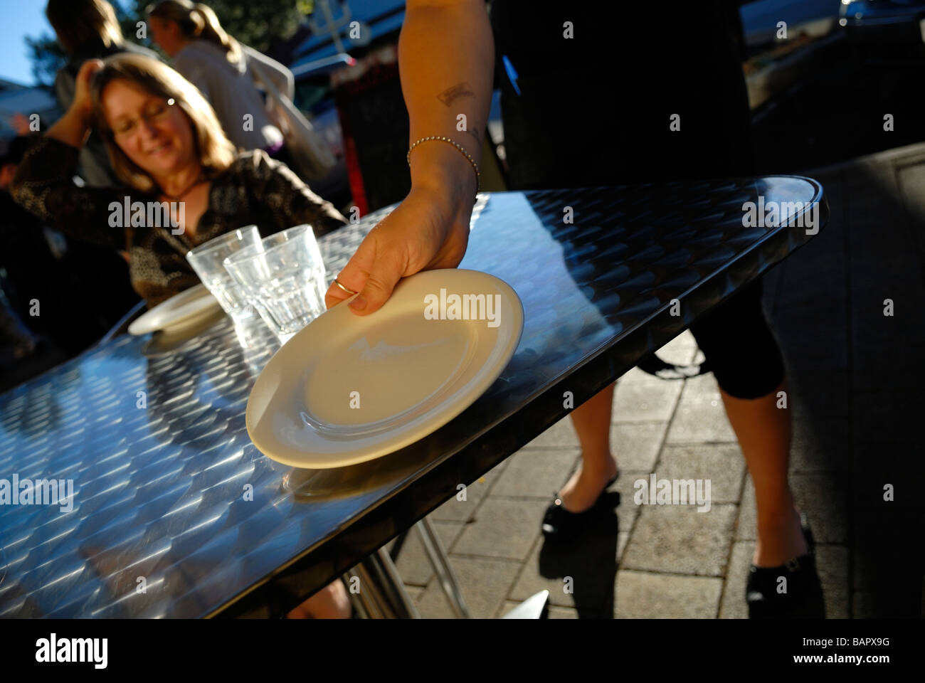 Waitress setting table at sidewalk restaurant. Fremantle, Perth, Western Australia, Australia Stock Photo