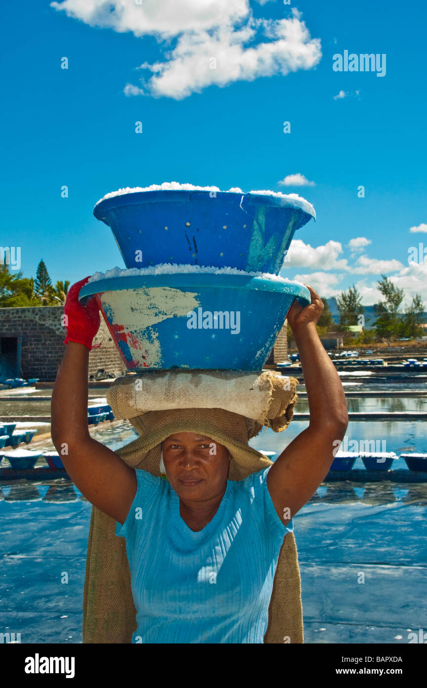 Salt production, woman carrying salt in front of salt pans near Tamarin Mauritius Stock Photo