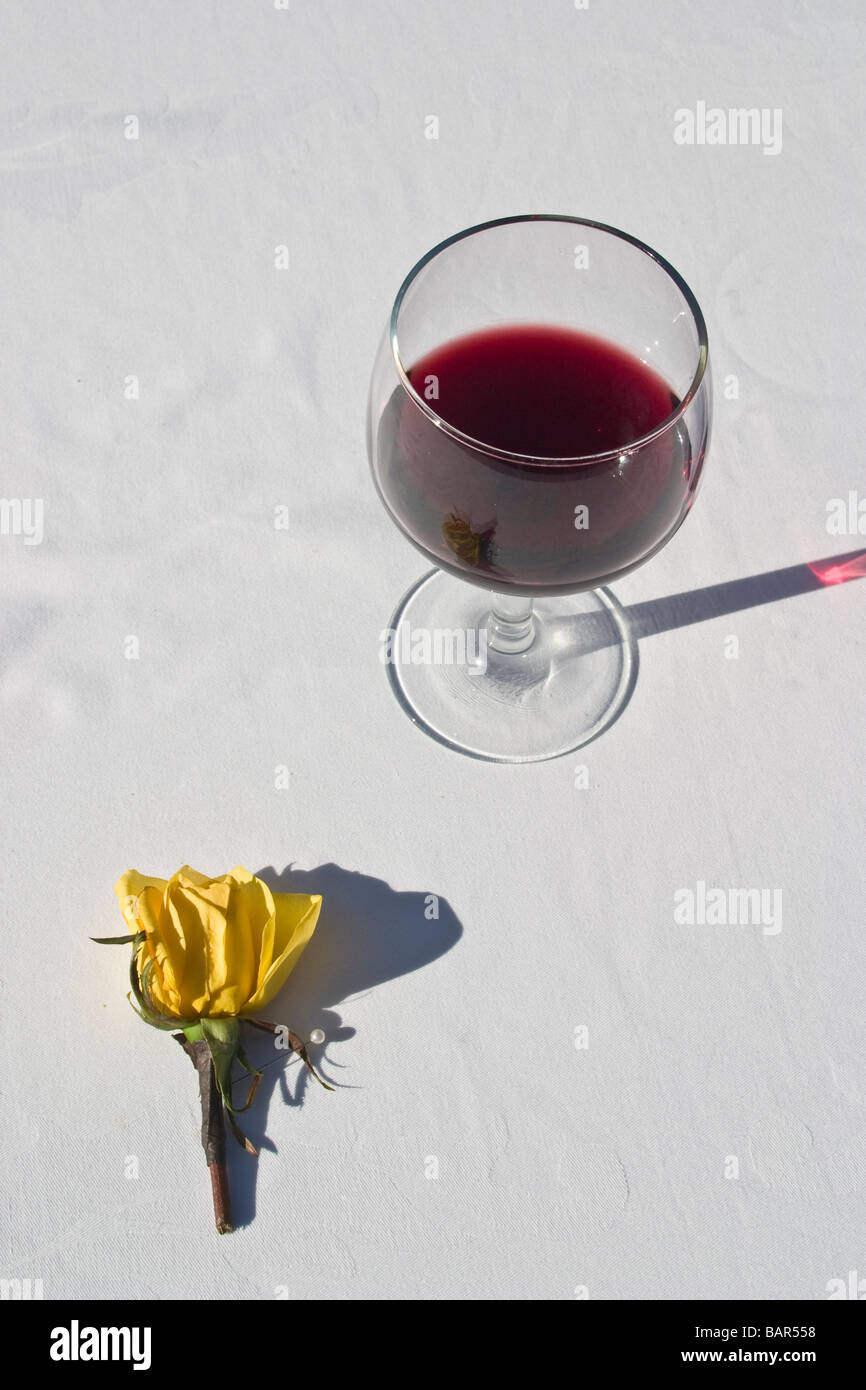 Glass of red wine and a yellow carnation Stock Photo