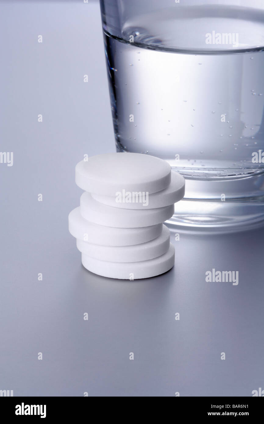 Ein Stapel Aspirin Tabletten mit Wasserglas A Pile Aspirin tablets with water glass Stock Photo